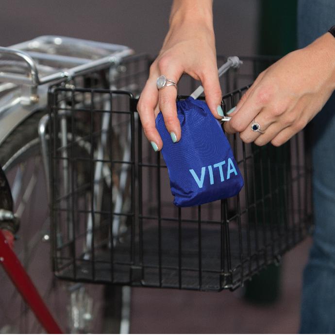 Mazarine Blue Vita Polyester reusable shoulder tote pouched and being clipped to the front of a bike basket
