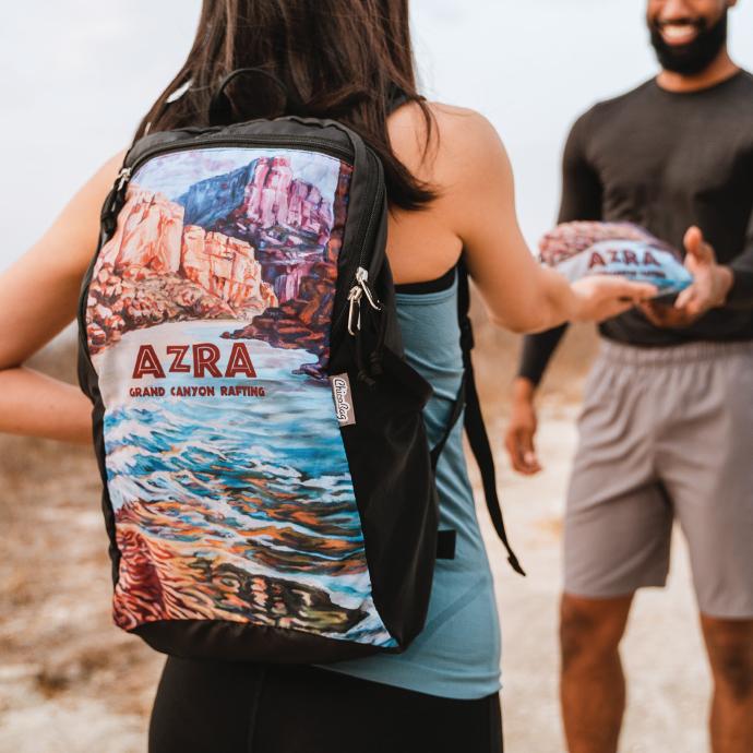 person wearing a azra grand canyon rafting custom ChicoBag travel Pack rePETe pouchable travel pack backpack handing a pouched ChicoBag travel pack to another person