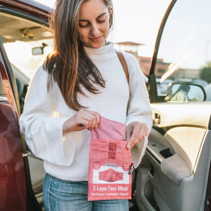 Woman getting out of her car looking down at her ChicoBag washable reusable 3 layer desert coral print facemask