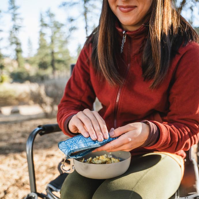 person sitting at a campsite preparing to eat with their To-Go Ware premium Shibori Moon utensil set 