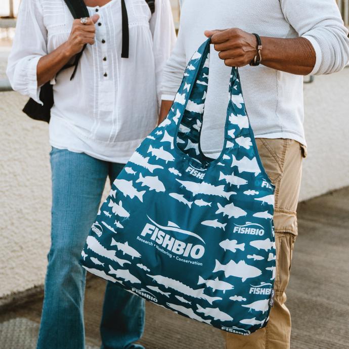 Two people standing and one is holding a Custom ChicoBag Vita Eco Friendly Reusable Tote from FishBio