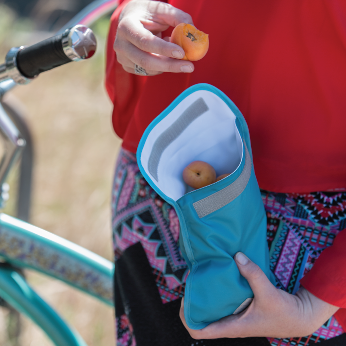 Person taking some fruit out of a ChicoBag adjustable snack time snack bag standing next to a bike