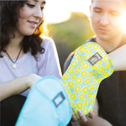 couple of people eating snacks out of a ChicoBag reusable and adjustable snack time lemon printed bag